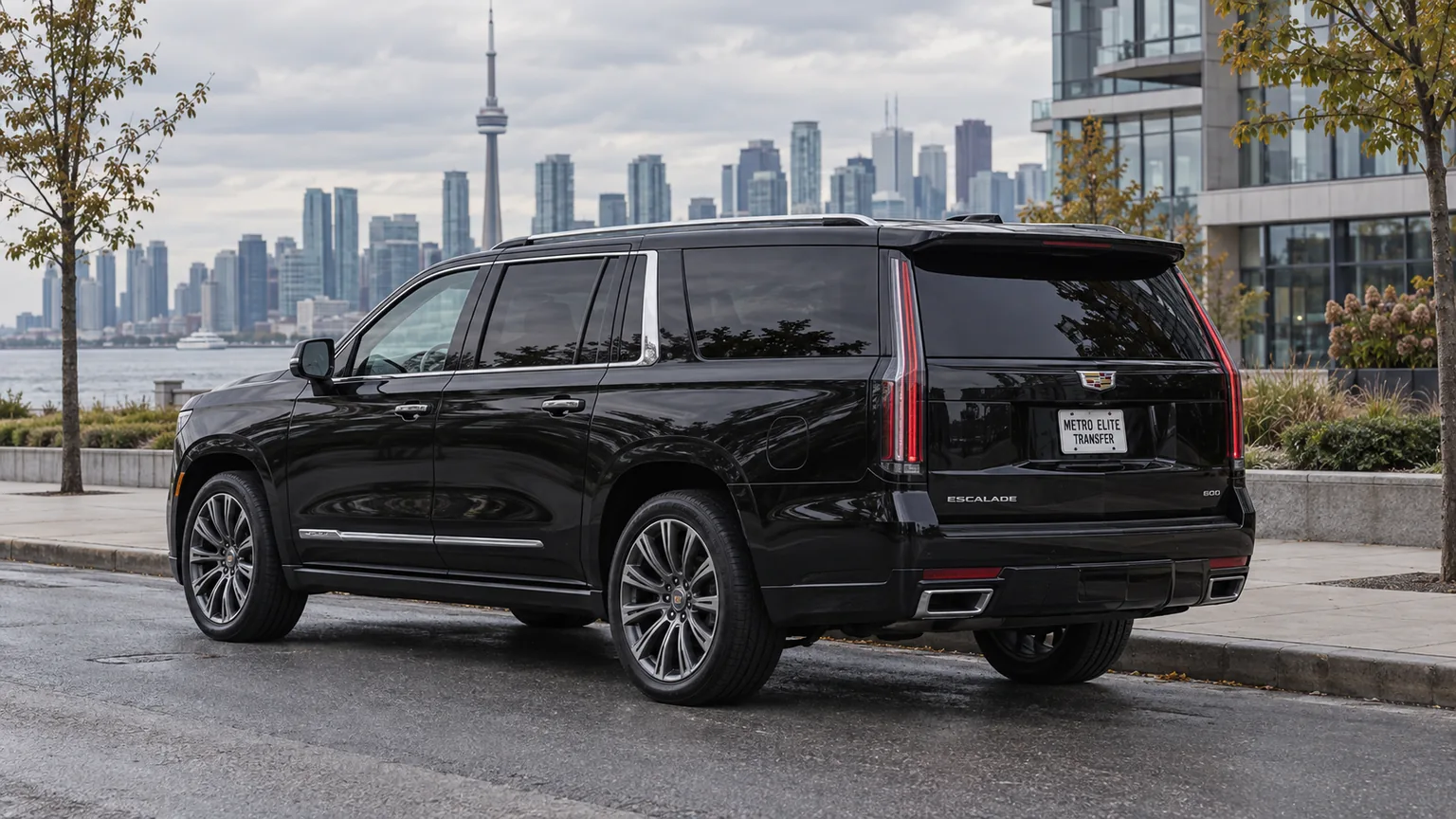 A black Cadillac Escalade ESV with a Metro Elite Transfer plate in an urban setting with a distant skyline