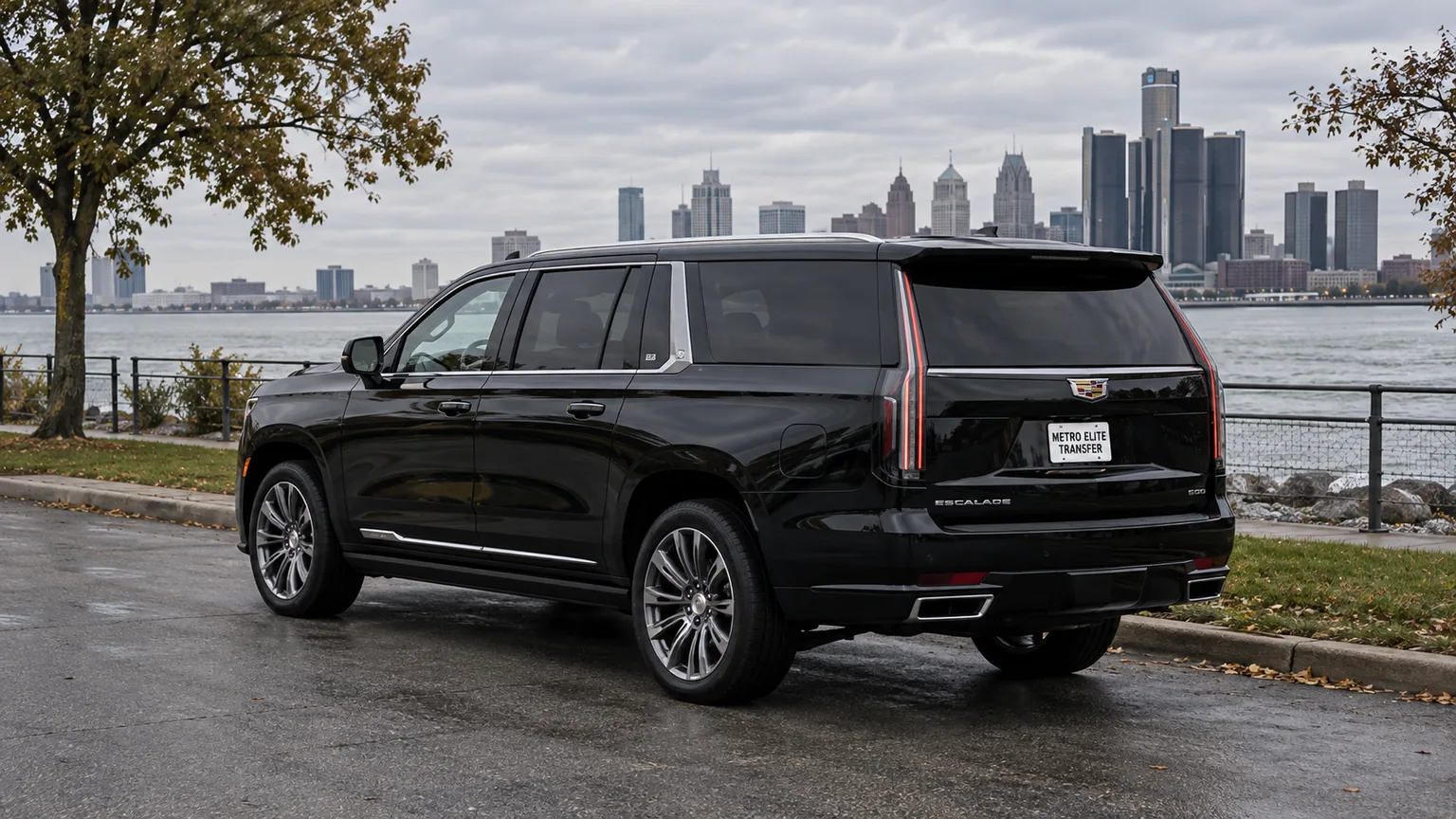 Black Cadillac Escalade ESV with a Metro Elite Transfer plate beside the river, with a distant city skyline